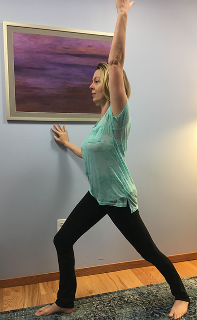 Using the wall for support while doing Warrior 1 pose during prenatal yoga