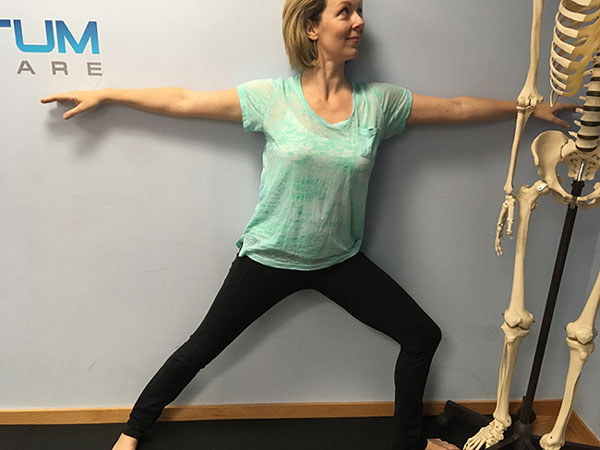 Lean against the wall for support while doing Warrior 2 pose during prenatal yoga
