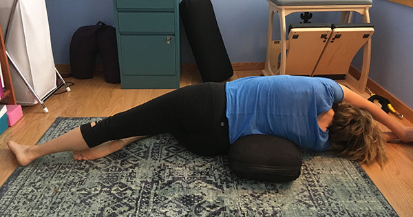 Half Moon pose on side with one leg extended using a bolster